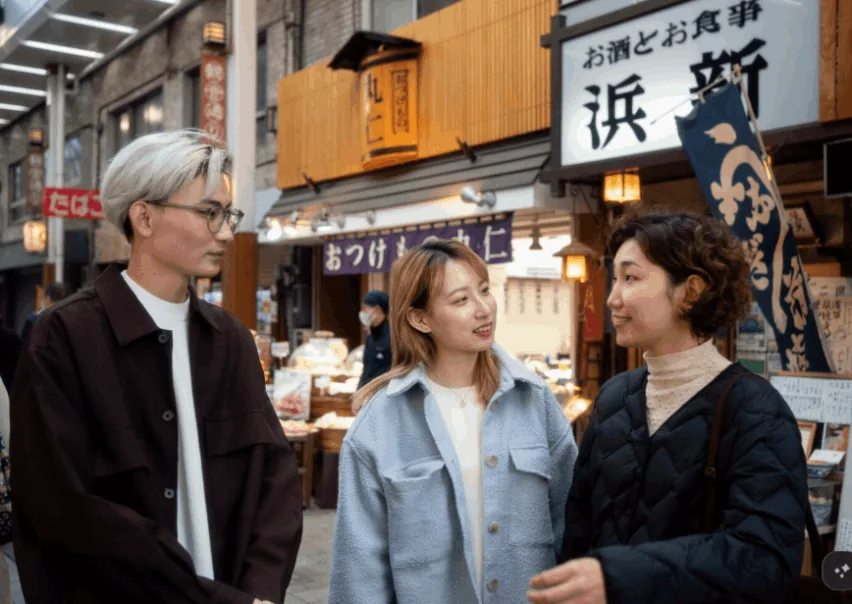 商店街の食事処の前で話す三人